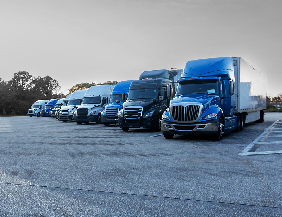 Stryder Logistics North American partner fleet with blue and white tractors and trailers including parked dry vans, reefers, flatbeds, roll-tites, chassis and more